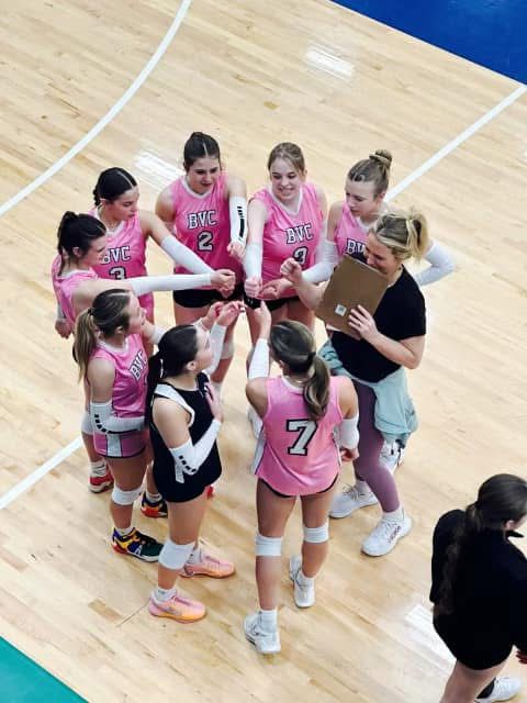 Players in pink BVC jerseys huddling with their coach