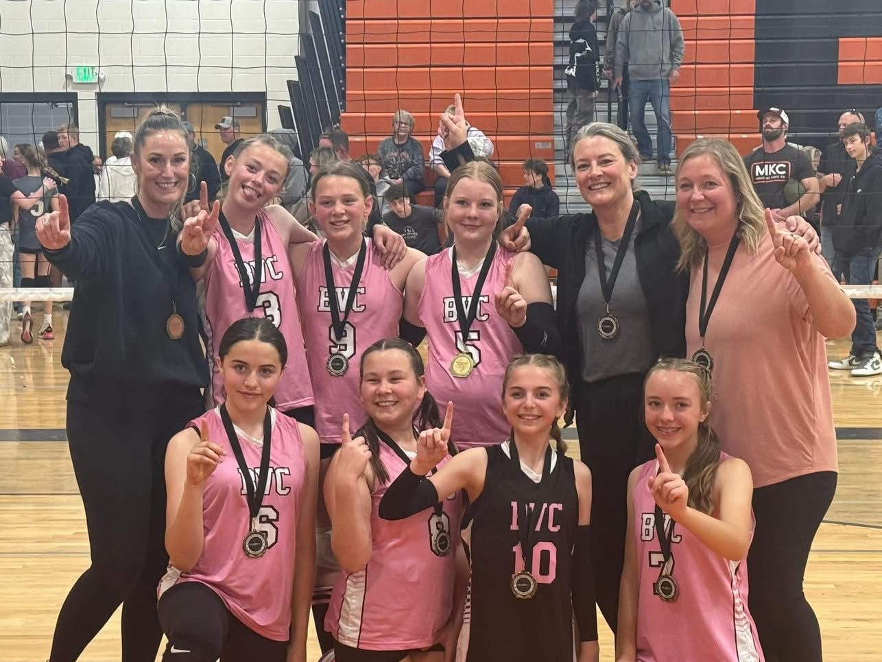 BVC players in pink jerseys and their coaches holding up medals after a tournament