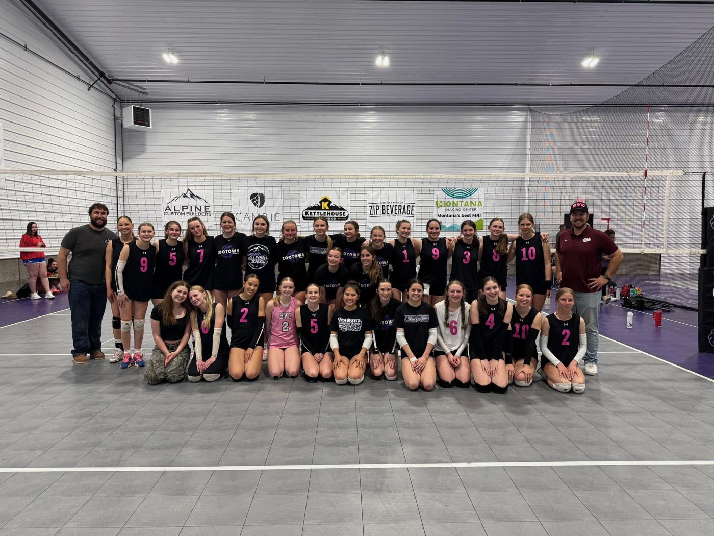 A large group of club players and coaches posing on a tournament court